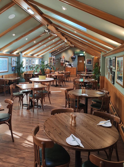 The Caff&egrave; Bar — timber-beamed ceiling, sage green walls, bentwood chairs and gallery walls