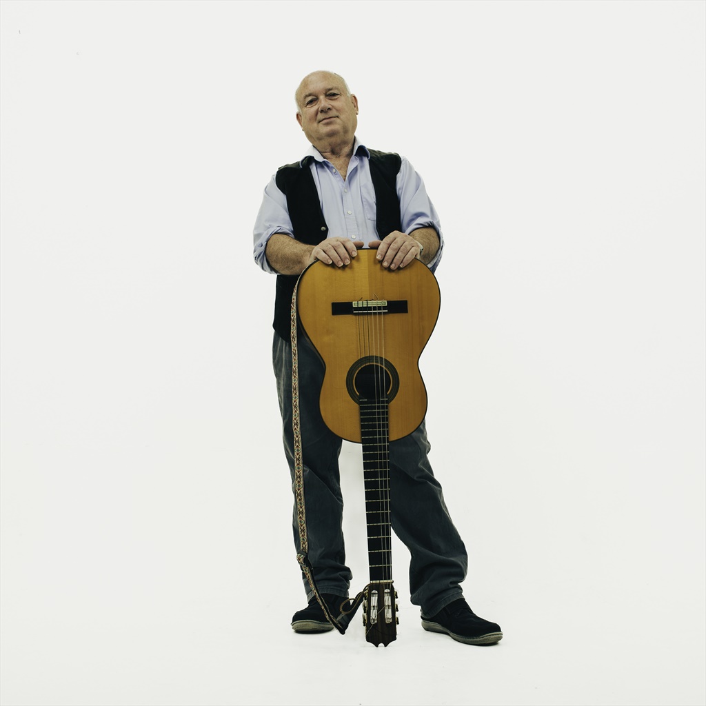 Louis de Berni&egrave;res standing with his guitar against a white studio background
